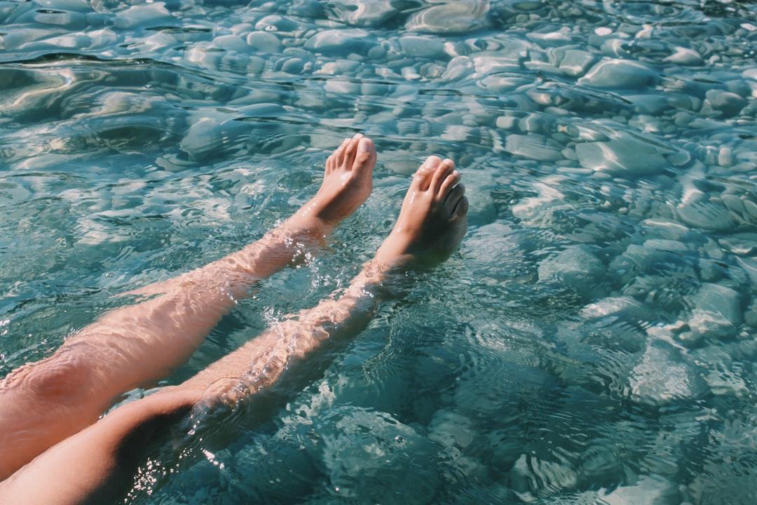 Close-up of a person's smooth legs as they float in a river, illustrating the benefits of laser hair removal.